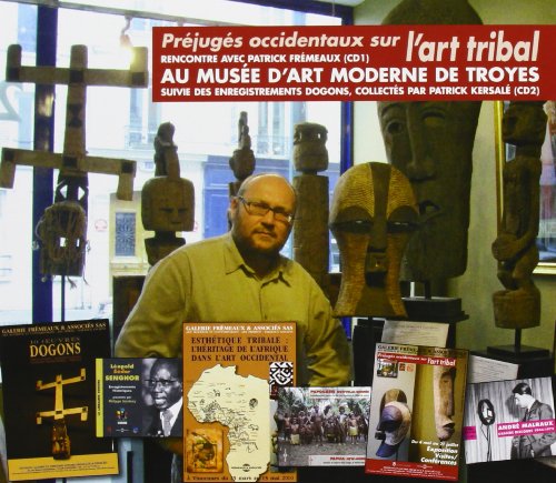 Man stands amongst African tribal masks and book covers in a museum.