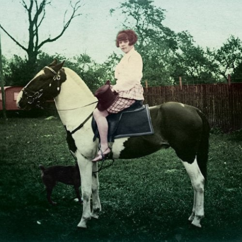Woman in pink riding a paint horse in a yard.