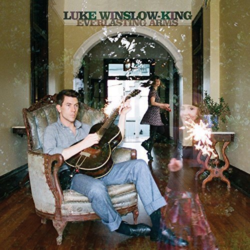 Vinyl album cover with man playing guitar in ornate chair, woman in background.