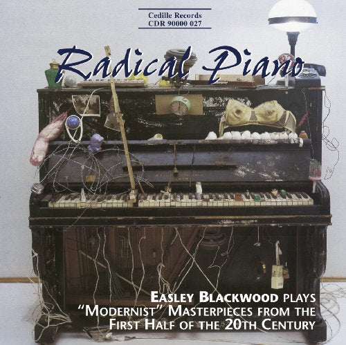 "Album cover featuring a damaged piano with various objects inside and wires."