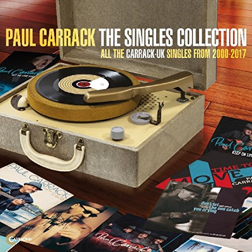 Vintage record player on wooden floor surrounded by Paul Carrack's album covers.