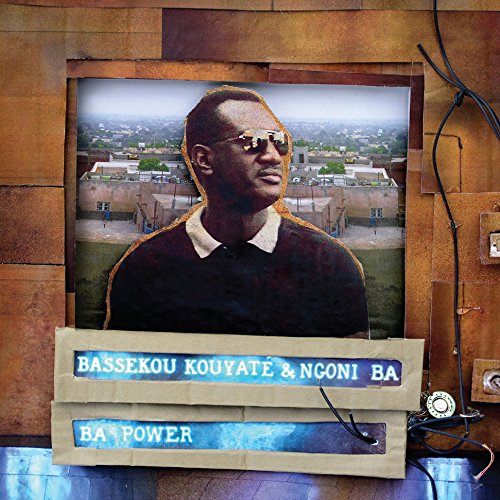 Vinyl album cover with a man in sunglasses and cityscape in the background.