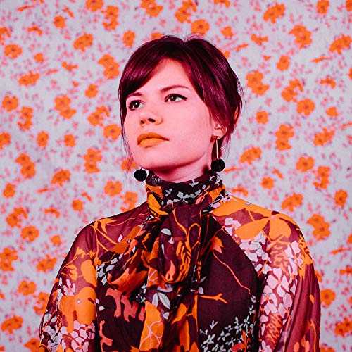 Woman with dark hair and orange floral patterned background.