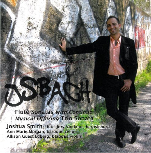 Man in black suit stands by graffiti wall, smiling, on album cover.