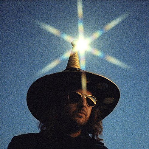 Man with sunglasses and wide-brimmed hat under a starburst sky.