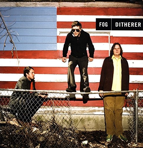 "Album cover featuring three men standing near a chain-link fence with a painted wall."