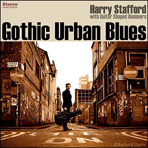 "Album cover with man holding guitar case in an alleyway between brick buildings."