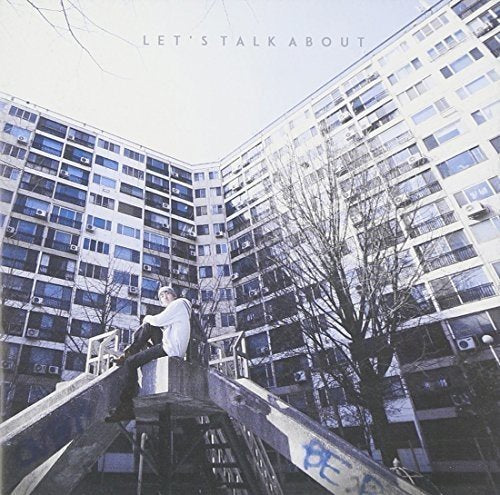 CD cover: person sitting on concrete near large apartment buildings.