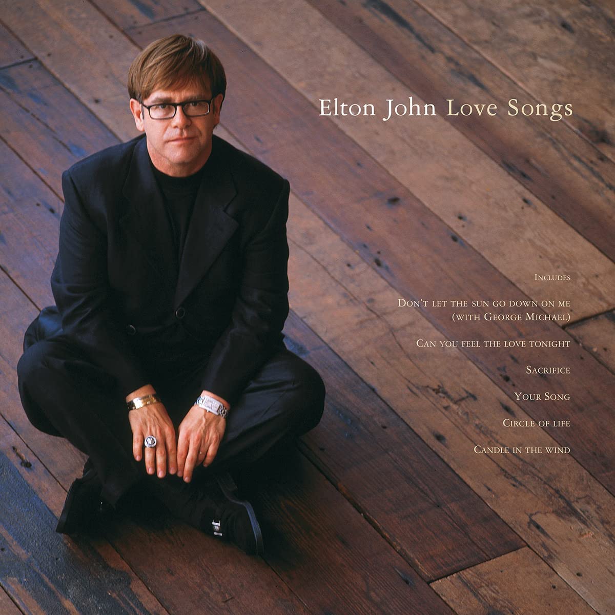 Vinyl album cover featuring Elton John crouching on wooden floorboards, wearing black suit.