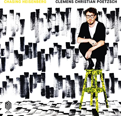 Man with glasses sits on a yellow stool against a textured background.