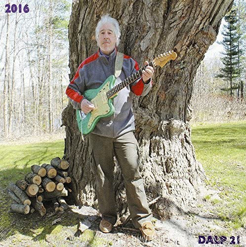 Danny Adler poses with a green guitar leaning against a tree.