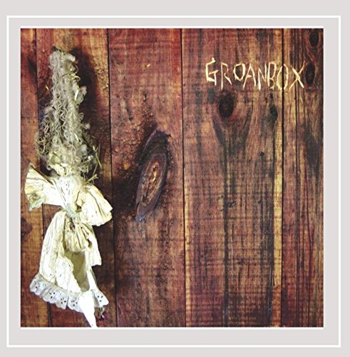 A sage bundle tied with cloth hangs on a dark wooden wall with "Groanbox" written.