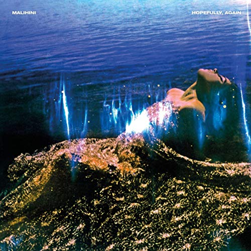 A person floats in dark water with glowing, light-refracting fabric over their body.
