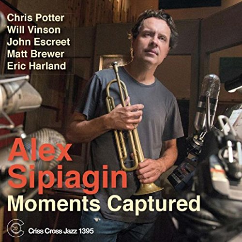 Man holding trumpet in recording studio, surrounded by microphones, on album cover.