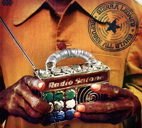 "Man holding a decorated radio with 'Radio Salone' label and antenna, wearing a brown shirt."