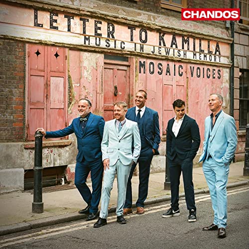 Five men in suits stand before a weathered red building facade.