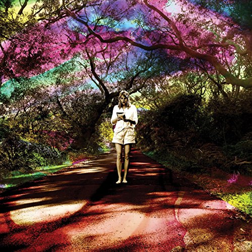 A woman walks down a path surrounded by trees with a vibrant, multicolored effect.