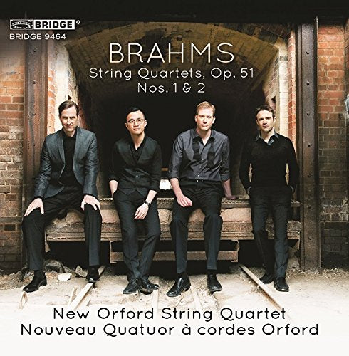"CD cover featuring four men in dark clothing posing by a brick archway."