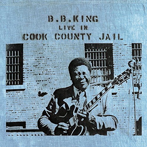 B.B. King playing guitar in front of a jail cell window.