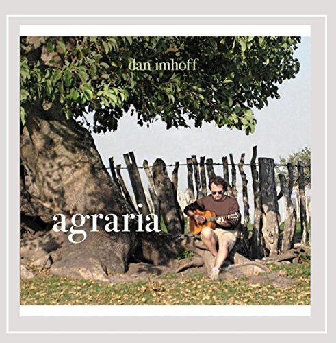 "Album cover with man sitting under tree, playing guitar, surrounded by wooden fence."