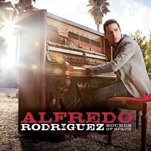 Man sitting at an open upright piano outdoors, with text "Alfredo Rodriguez Sounds of Space".