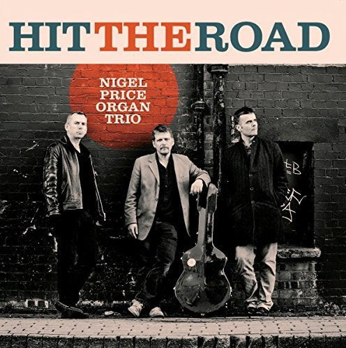 "Album cover with three men standing by a brick wall, holding instruments."