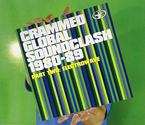 "Hand holding a CD case with striped blue and green cover on green background."