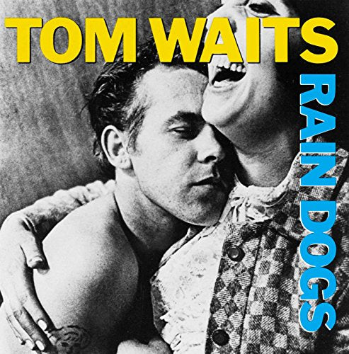 Black and white photo of Tom Waits embracing someone, album title in yellow and blue.