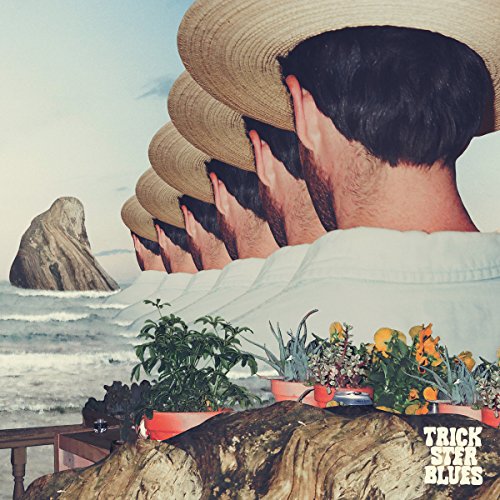 Row of people in straw hats overlooking ocean and flowers.