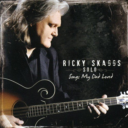 "CD cover with Ricky Skaggs holding a guitar, grey hair, dark attire."