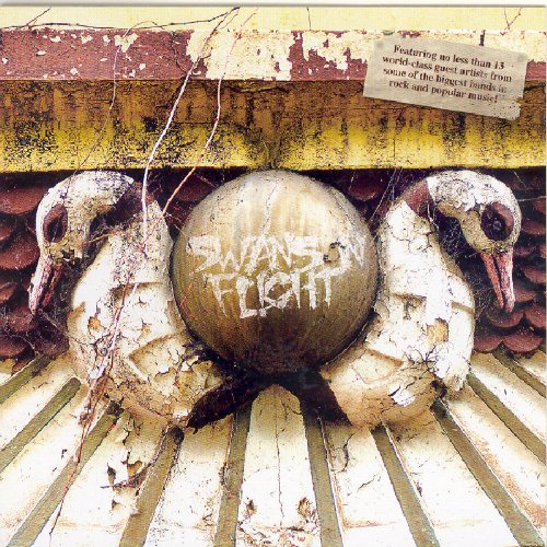 "Damaged stone swans with 'Swanson Flight' graffiti on a ball between them, on a ledge."