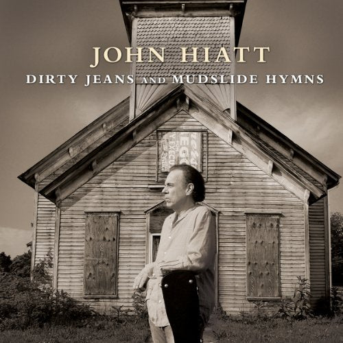 John Hiatt stands before a weathered, rural church in sepia tones.