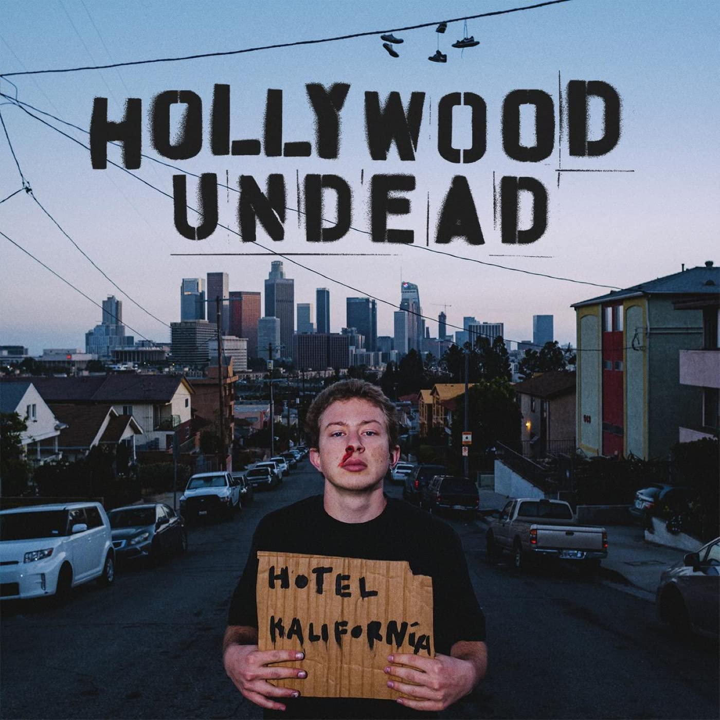 "Album cover with man holding a 'Hotel Kalifornia' sign, cityscape in the background."