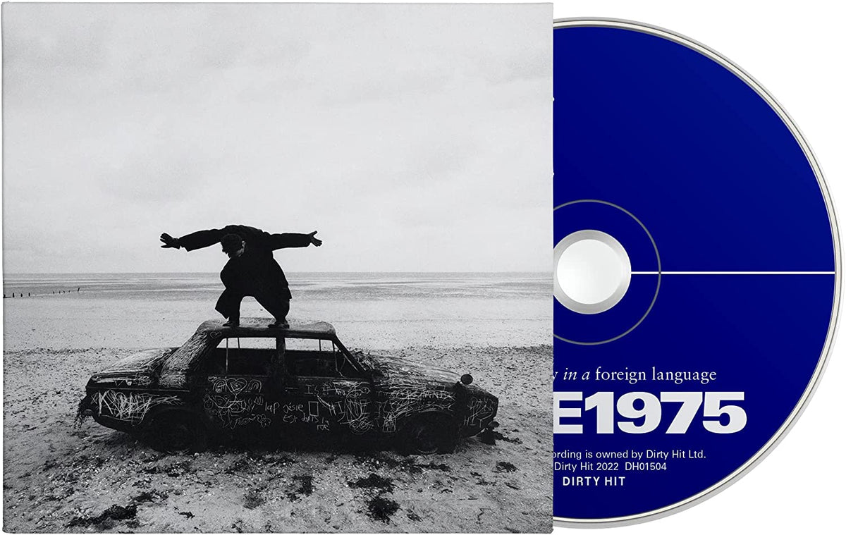 Black and white CD cover: person on a wrecked, graffitied car.