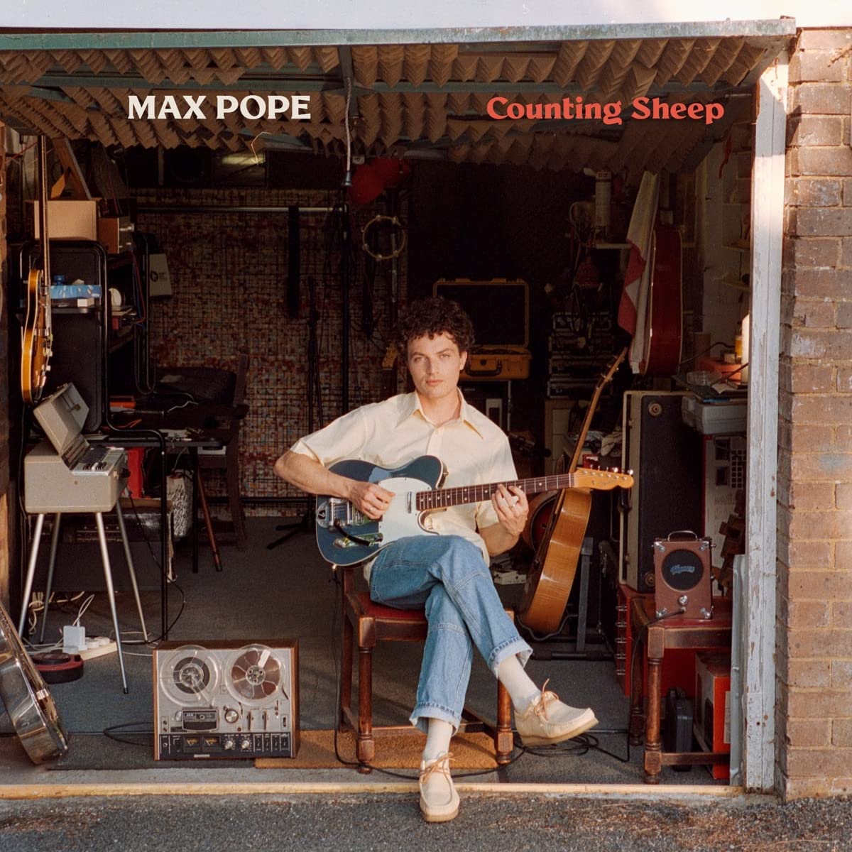 CD cover: Max Pope sits with a guitar in a cluttered garage.