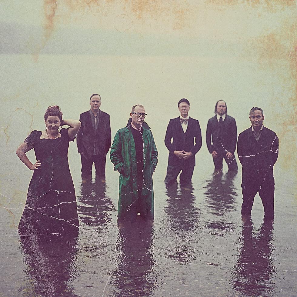 Six people stand in water, vintage-style album cover for “Stars.”