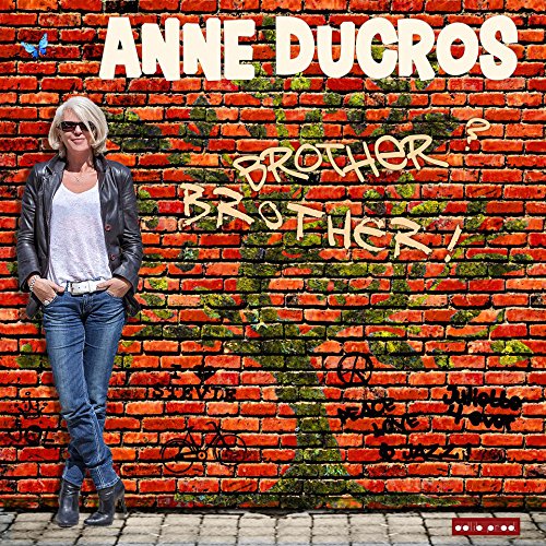 Album cover featuring a woman standing against a graffiti-covered brick wall with text.