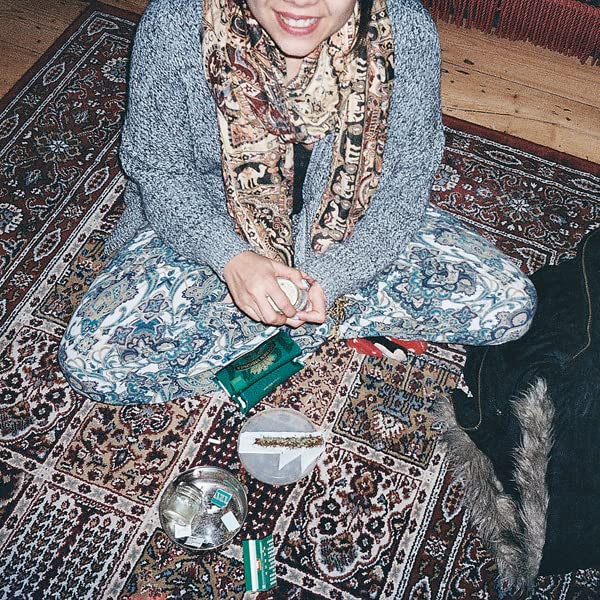 Woman sitting cross-legged on a rug with vinyl records nearby.