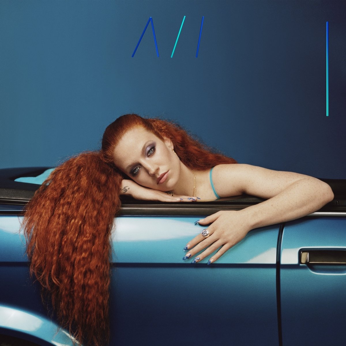 Jess Glynne album cover: red-haired woman leaning on blue car against blue background.