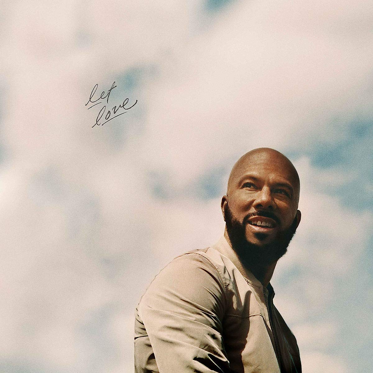 Album cover with a smiling bald man against a cloudy sky background.