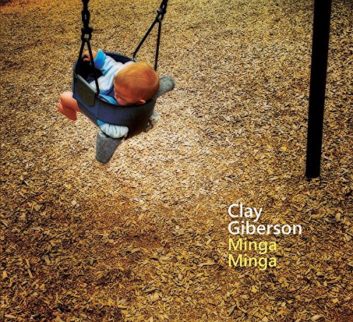 Album cover with a baby in a swing on woodchips, artist and title text overlay.