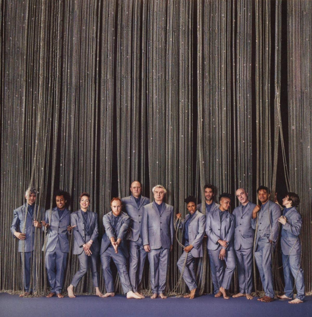"CD cover art for 'American Utopia' featuring 11 men in gray suits standing together."