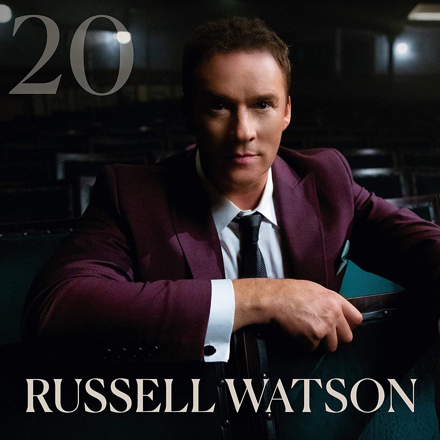 "Album cover featuring Russell Watson in a maroon suit, holding a chair."