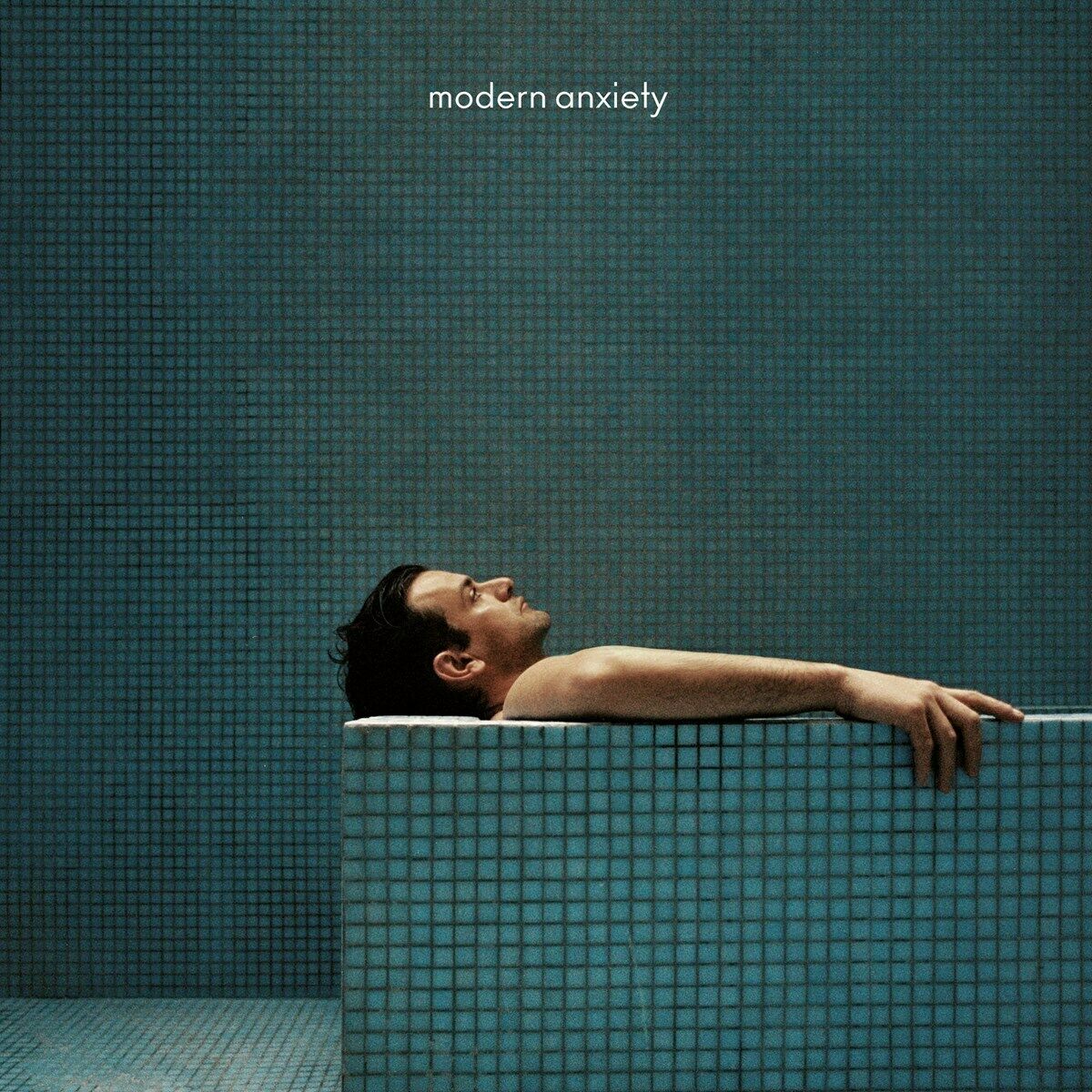 Album cover with man in tiled bathtub, "modern anxiety" text above, against tiled wall background.