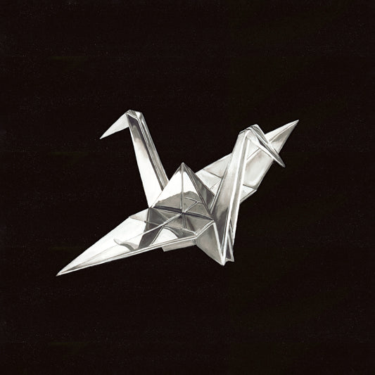 Silver origami crane against a black, speckled background.