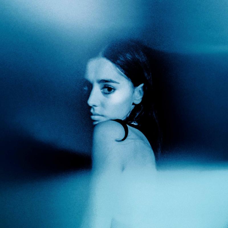 Blue-toned portrait of a woman with dark hair, looking to the side.