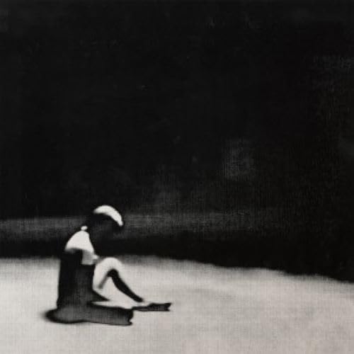 Black and white photo of a person sitting in a field.