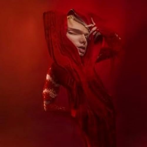 Person with pale face and red hooded garment, dramatic lighting.
