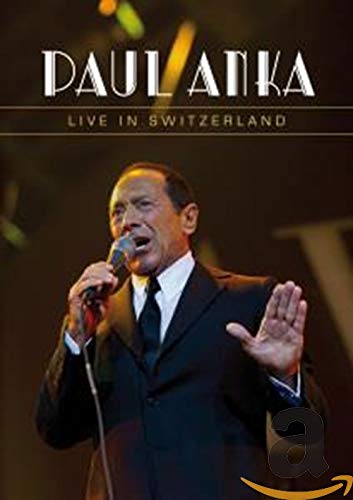 Paul Anka singing into a microphone on a concert stage.
