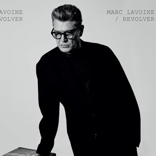 Black and white portrait of Marc Lavoine wearing glasses and a black blazer.